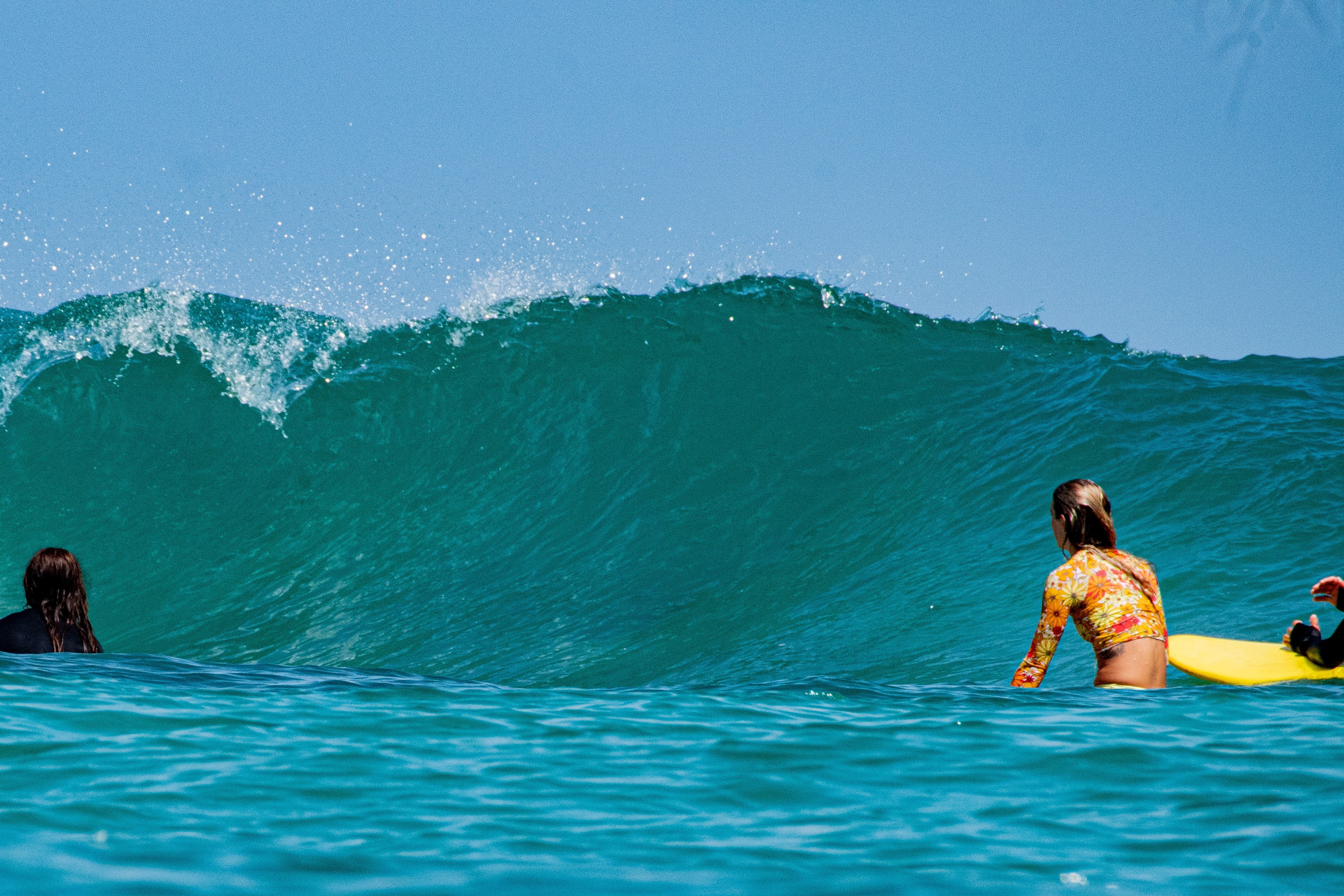 Surfer girl sitting in the water at Carenero, Bocas del Toro, Panama